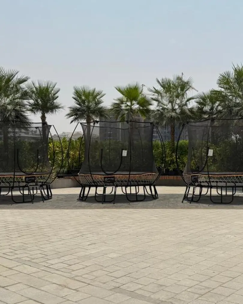 Paved courtyard with palms and trampolines between the buildings