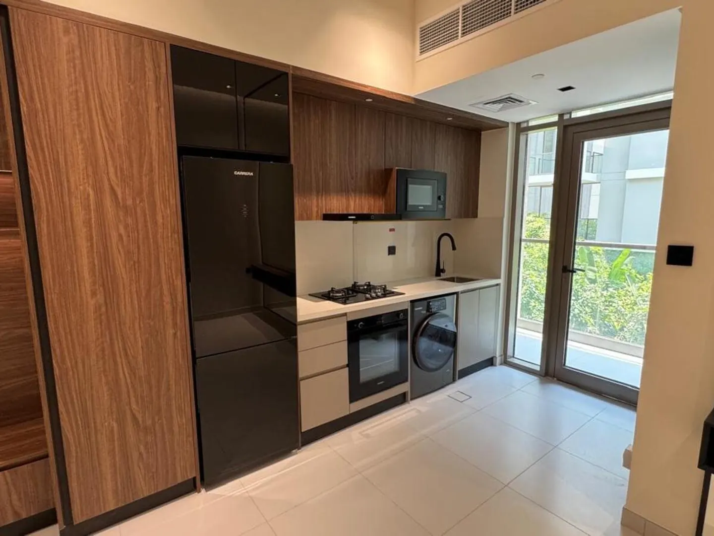 Studio at Torino, Building 3: walnut joinery, fitted kitchen and glass doors onto the balcony